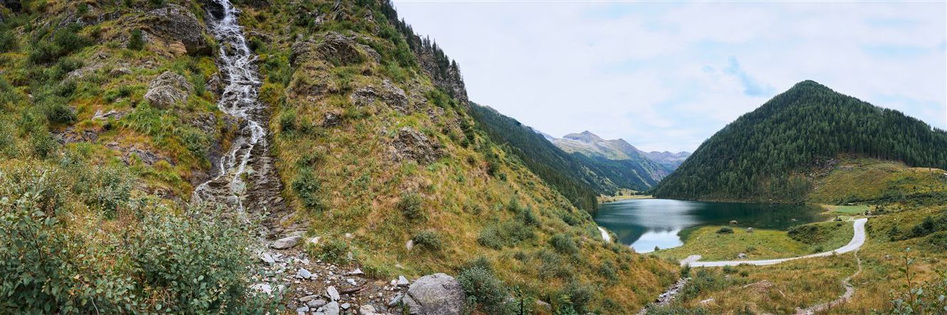 Panoramabild vom Riesachsee und einem kleinen Wasserfall zwischen Bergen