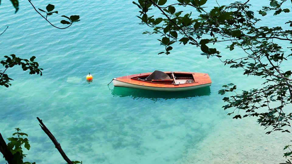 Ein Boot in der Nähe des Ufers auf einem türkisblauen See, eingerahmt von Blättern